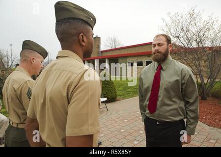 Cpl. Nathan Bryson (right), a Marine Corps veteran who most recently served as a motor transport operator for Headquarters and Support Battalion, School of Infantry East, Camp Lejeune, North Carolina, stands at attention across Col. Ricardo Player (center), the Force Headquarters Group chief of staff, Marine Forces Reserve, while Sgt. Maj. William Grigsby (left), the sergeant major of FHG, MARFORRES, reads off a citation for Bryson’s Navy and Marine Corps Medal ceremony in Brook Park, Ohio, April 13, 2017. In 2014, Bryson and a fellow Marine aided in saving a man from a burning vehicle, riskin Stock Photo