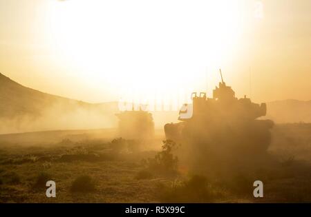 M1A2 Abrams Main Battle Tanks from 1st Battalion, 64th Armor Regiment continue their attack as the sun begins to set at the National Training Center at Fort Irwin, California April 13. The 1st Armored Brigade Combat Team, 3rd Infantry Division’s decisive action rotation at the National Training Center tested the brigade’s systems and capabilities as they fought a near-peer enemy threat. Stock Photo