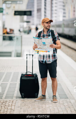 Tourist backpacker using map to travel at train station Stock Photo
