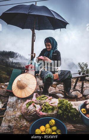 Old lady sellimng food and vegetables in the mountains of Sapa, Vietnam Stock Photo