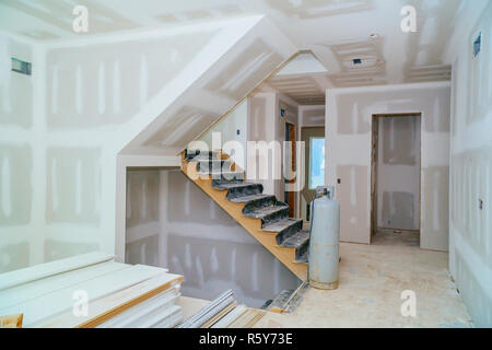 Wheelbarrow is in front of tools for ground work for dry wall are stacked on ground in background. Stock Photo