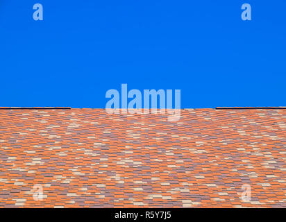 Roof from multi-colored bituminous shingles. Patterned bitumen shingles. Stock Photo