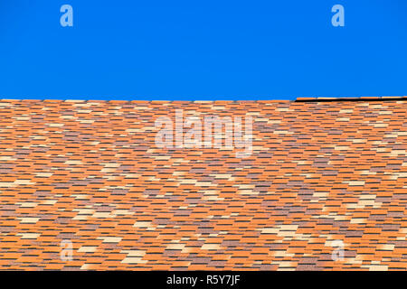 Roof from multi-colored bituminous shingles. Patterned bitumen shingles. Stock Photo