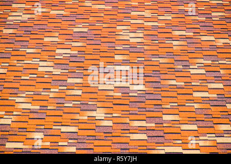 Roof from multi-colored bituminous shingles. Patterned bitumen shingles. Stock Photo