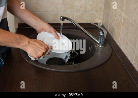 Image of side of man's hands washing transparent mug in sink Stock Photo