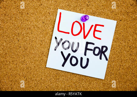 A yellow sticky note writing, caption, inscription Phrase LOVE YOU FOR YOU in black ext on a WHITE sticky note pinned to a cork notice board Stock Photo