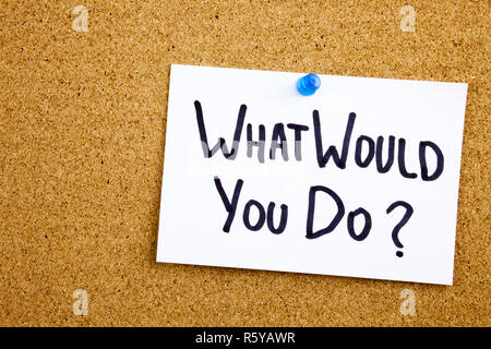 A yellow sticky note writing, caption, inscription Phrase WHAT WHOULD YOU DO in black ext on a sticky note pinned to a cork notice board Stock Photo