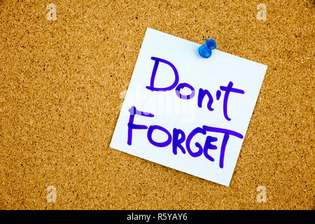 A yellow sticky note writing, caption, inscription don't forget written on color sticker notes over cork board background Stock Photo