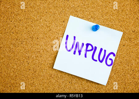 A yellow sticky note writing, caption, inscription unplug, motivational lifestyle reminders against black ext on a colorful sticky note pinned to a cork notice board Stock Photo