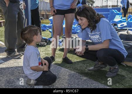 Cassandra Carag, location general manager for CarMax of Escondido, right, plays with the children of the Armed Services Young Men's Christian Association (ASYMCA), Fisher Children's Center, during a 'Week of Play' event on Camp Pendleton, Calif., April 20, 2017. The ASYMCA, Fisher Children's Center, was awarded a Kaboom Play Grant from the CarMax Foundation for Military Child Month where an 'imagination playground' was revealed. Stock Photo