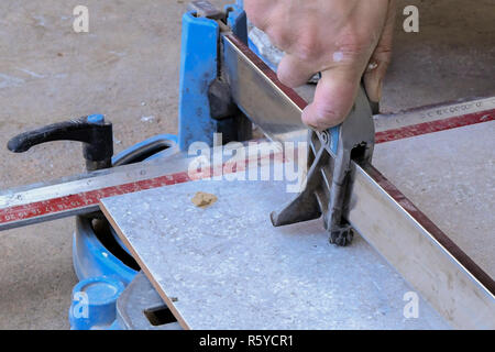 Cutting ceramic tile. Worker placing a big ceramic tile in a cutter and cutting Stock Photo