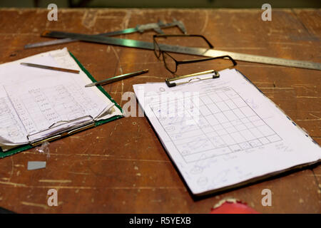 Clipboards with order notes on workshop table in metalwork factory Stock Photo