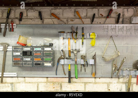 Old tools hanging on wall in metalwork workshop , Tool shelf against a wall Stock Photo