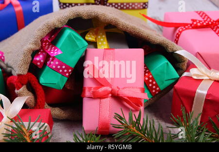 Wrapped gifts for Christmas, birthday or other celebration in jute bag and green spruce branches Stock Photo