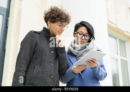 Multi-ethnic colleagues discussing online report outdoors Stock Photo