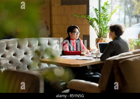 Busy ladies talking in modern cafe Stock Photo
