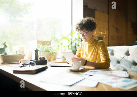 Serious woman in glasses working in cafe Stock Photo
