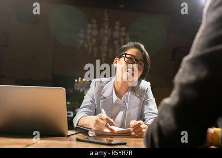Asian lady working with colleague in dark office Stock Photo