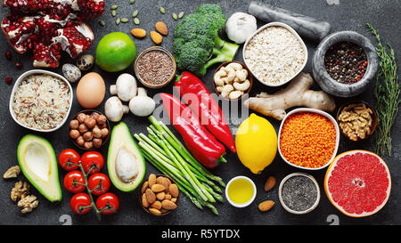 Healthy food clean eating selection: fruit, vegetable, seeds, superfood, cereal, leaf vegetable on black concrete background Flat lay Stock Photo