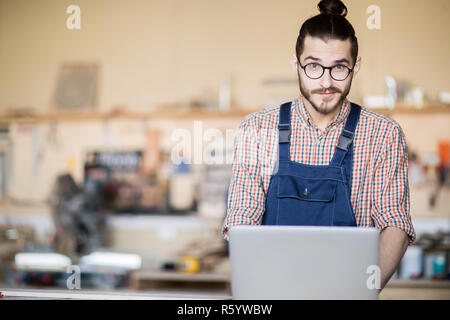 Contemporary Man using Laptop in Workshop Stock Photo
