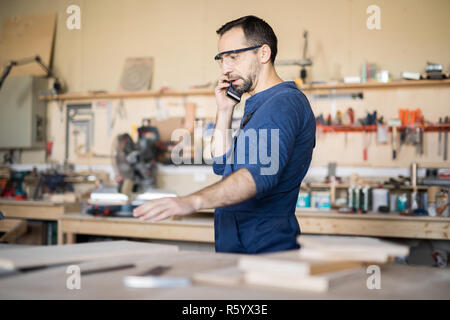 Worker Speaking by Phone in Joinery Stock Photo