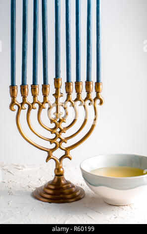 Menorah brass Hanukkah with blue candles and butter in a bowl Stock Photo
