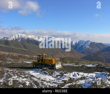 Crawler tractor with grederom against the backdrop of snow-cappe Stock Photo