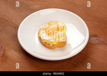 A photo of a quail egg, fried sunny side up, on a cracker, on a dark rustic wooden background Stock Photo