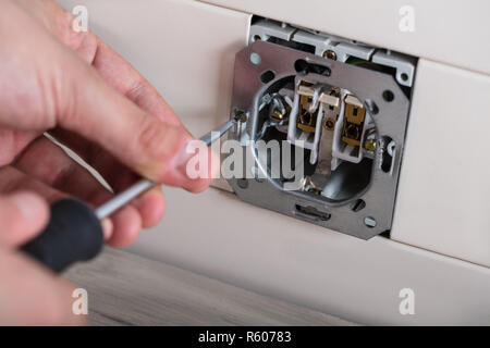 Person's Hand Repairing Electrical Socket Stock Photo