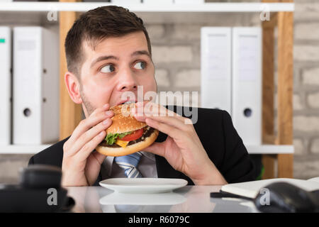 Handsome Young Businessman Eating Burger Stock Photo