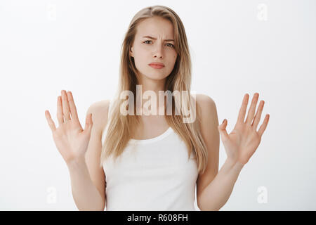 Stop, enough of lies. Portrait of displeased and sad cute bothered woman with fair hair frowning from dislike sweeping hands in enough and not gesture Stock Photo