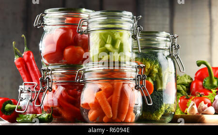 Jars with marinated food and organic raw vegetables Stock Photo