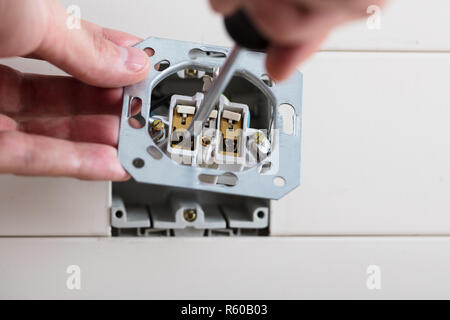 Person's Hand Repairing Electrical Socket Stock Photo