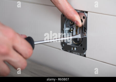 Person's Hand Repairing Electrical Socket Stock Photo