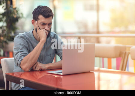Half length portrait of successful bearded designer smiling at camera while working on freelance at netbook. Stock Photo