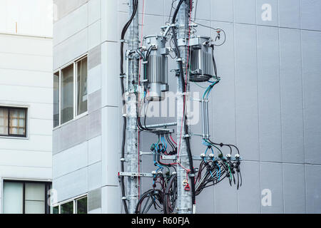 Modern poles with electricity cables on the background of a residential building, poles with electric wires, telecommunication pole .background. Stock Photo