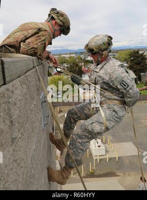 U.S. Army Sgt. Anthony Barba, 184th Headquarters and Headquarters Detachment (EOD), 184th Ordnance Disposal Battalion (EOD), 52nd Ordnance Group (EOD), prepares to lower himself during a vertical access training exercise at Yakima Fire Station 95, Yakima, Wash., April 25, 2017. The vertical access training is designed to create adaptive leaders capable of solving various threats in hostile and friendly environments. Stock Photo