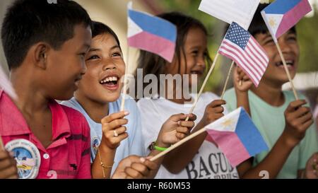 Filipino children wave U.S. and Philippine flags during a groundbreaking ceremony for Balikatan 2017 in Ormoc City, Leyte, April 25, 2017. Leaders from the Armed Forces of the Philippines, U.S. military, and Ormoc City gathered to commemorate the beginning of engineering projects for new classrooms at Margen Elementary School in Ormoc City. Balikatan is an annual U.S.-Philippine military bilateral exercise focused on a variety of missions, including humanitarian assistance and disaster relief and counterterrorism. Stock Photo