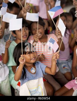 Filipino children wave U.S. and Philippine flags during a groundbreaking ceremony for Balikatan 2017 in Ormoc City, Leyte, April 25, 2017. Leaders from the Armed Forces of the Philippines, U.S. military, and Ormoc City gathered to commemorate the beginning of engineering projects for new classrooms at Margen Elementary School in Ormoc City. Balikatan is an annual U.S.-Philippine military bilateral exercise focused on a variety of missions, including humanitarian assistance and disaster relief and counterterrorism. Stock Photo