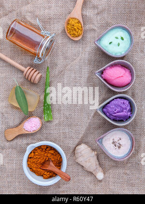 Alternative skin care and homemade scrubs with natural ingredients sage ,turmeric ,sea salt ,honey, aloe vera,lemon ,rosemary,mint and sesame set up on brown table. Stock Photo