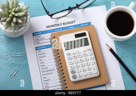 Monthly budget concept with white calculator and coffee cup on blue wooden table Stock Photo