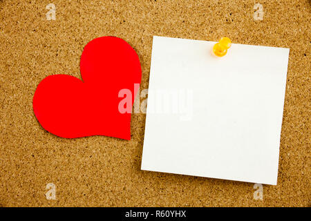 A yellow sticky note post it writing, caption, inscription empty in black ext on a sticky note pinned to a cork notice board Stock Photo