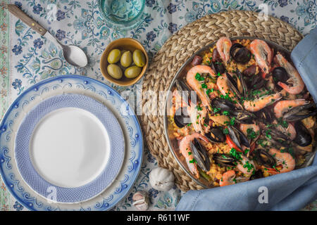 Paella on the metal plate on the beautiful napkin with tableware top view Stock Photo