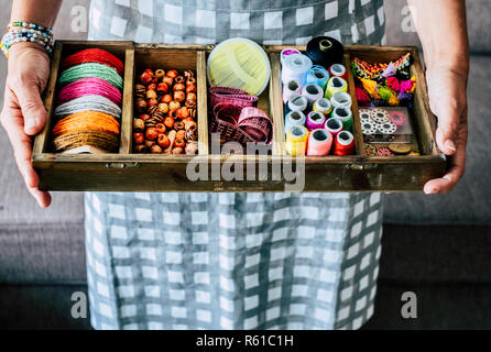 Above view of woman taking and showing fabrics buttons and accessories to make dress or jewels with a lot of colors and materiales - handcraft and han Stock Photo