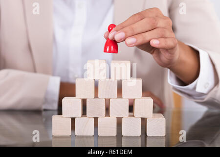 Businesswoman Placing Red Figure On Arranged Blocks Stock Photo