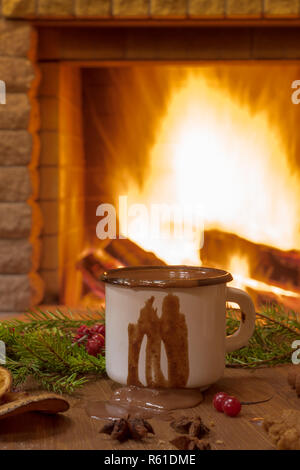 Christmas eve. White enameled mug with hot chocolate, near cozy fireplace, in country house, winter vacation.