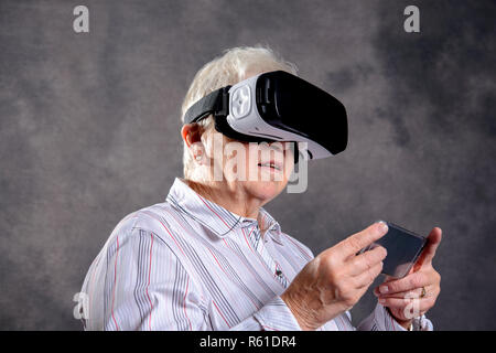 gray hairy elderly woman using virtual reality glasses Stock Photo