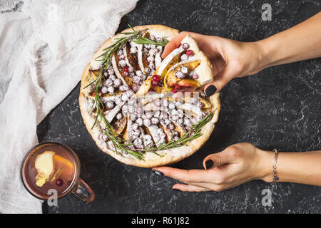 Woman's hands hold Apple pies with cranberry on black stone background. Top view. Stock Photo