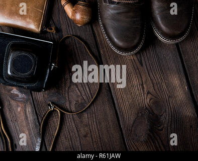 pair of leather brown shoes and an old vintage camera in a case on a wooden background, copy space Stock Photo