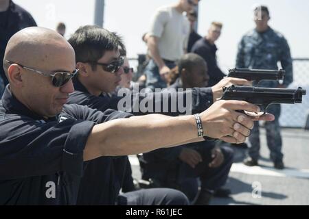 MEDITERRANEAN SEA (May 5, 2017) Lt. Jeremy Maldonado, front, demonstrates weapon familiarization before a 9mm pistol qualification aboard the Arleigh Burke-class guided-missile destroyer USS Ross (DDG 71) May 5, 2017. Ross, forward-deployed to Rota, Spain, is conducting naval operations in the U.S. 6th Fleet area of operations in support of U.S. national security interests in Europe and Africa. Stock Photo